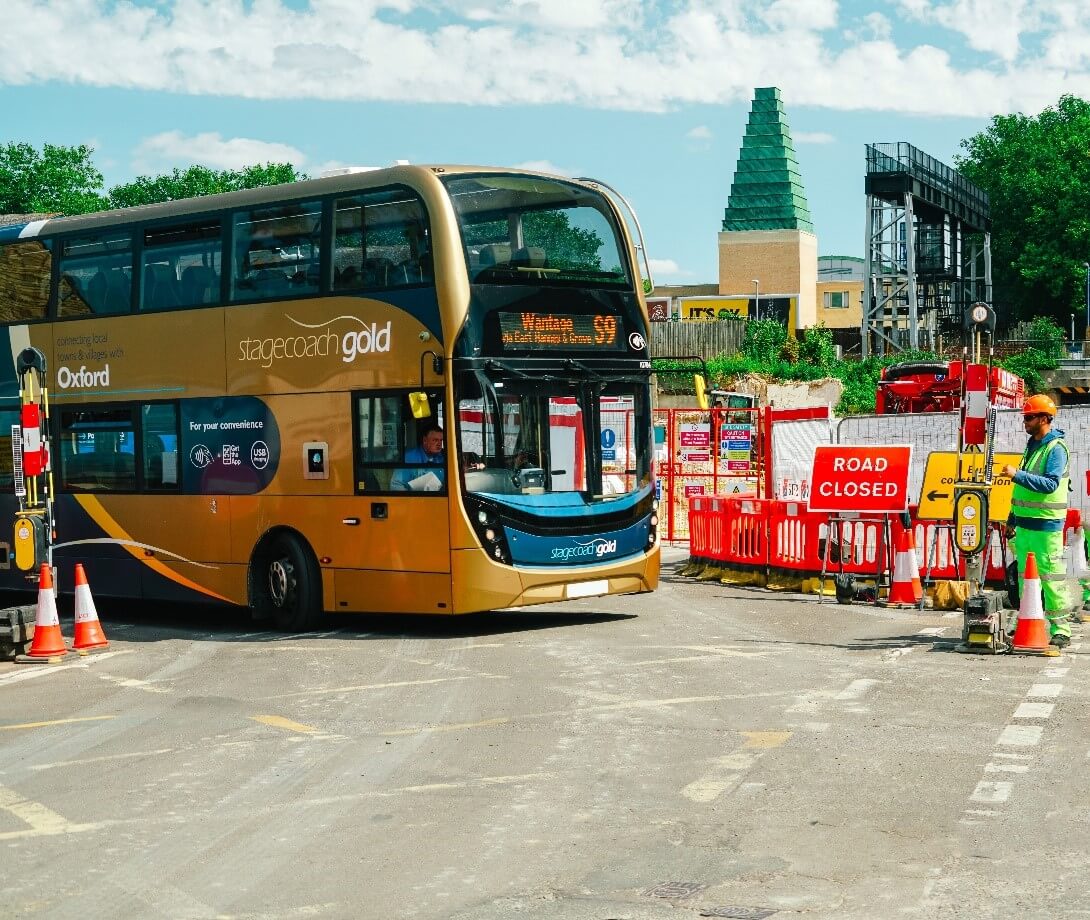 Coach driving up to SentriGate at Oxford Station expansion construction site