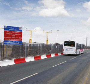 Bus driving past MASS Barriers and perimeter fencing installed for the Manchester Metrolink project